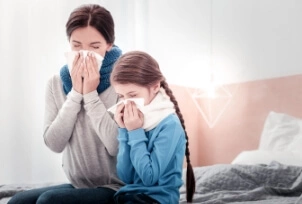 Przeziębiona mama i córka dmuchają nos w chusteczki | Osłonka