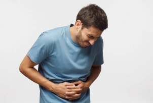 Mężczyzna z bolącym żołądkiem trzyma się za brzuch | Osłonka